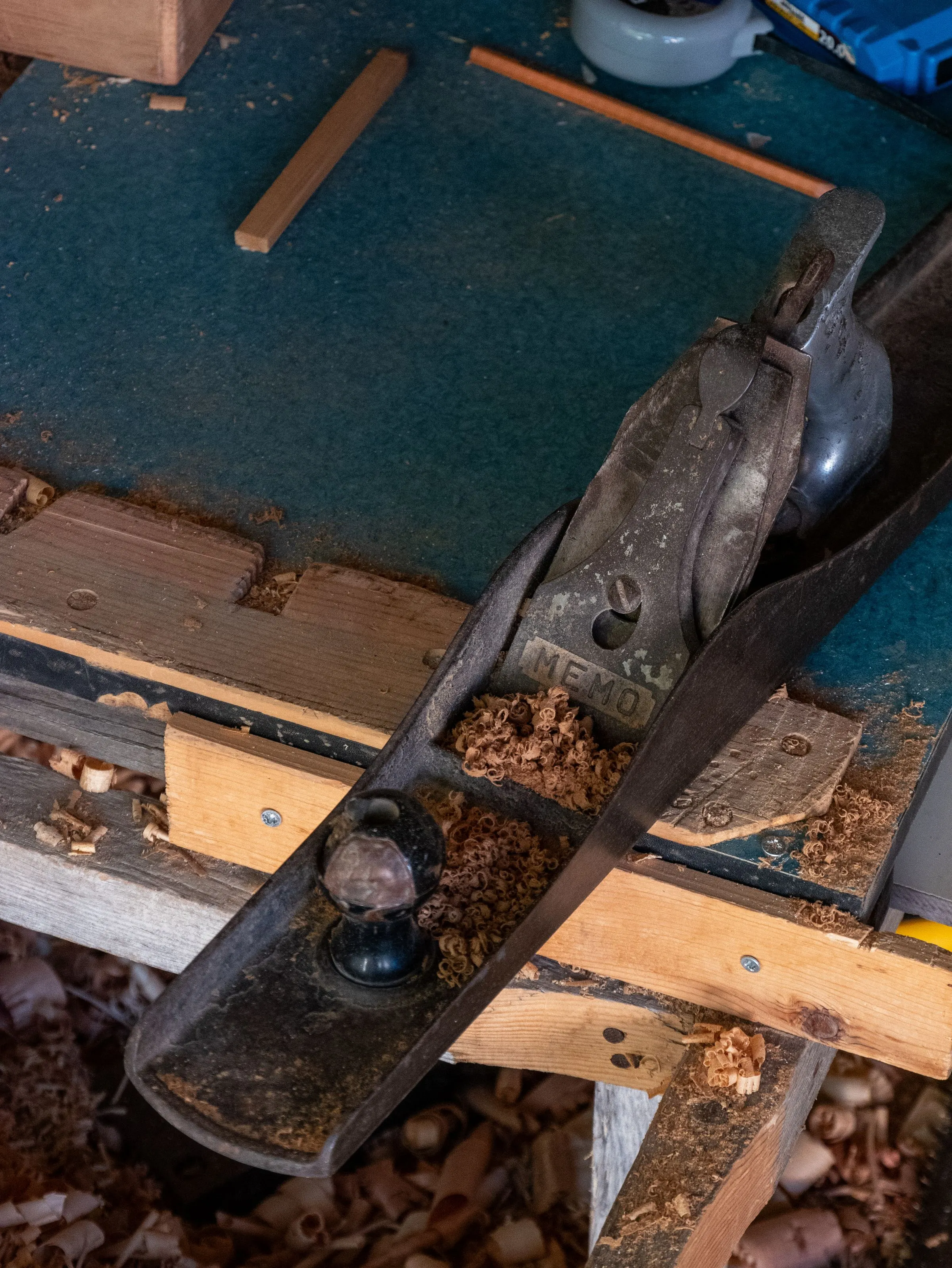 Een handschaaf op een werkbank, tussen de krullen hout.