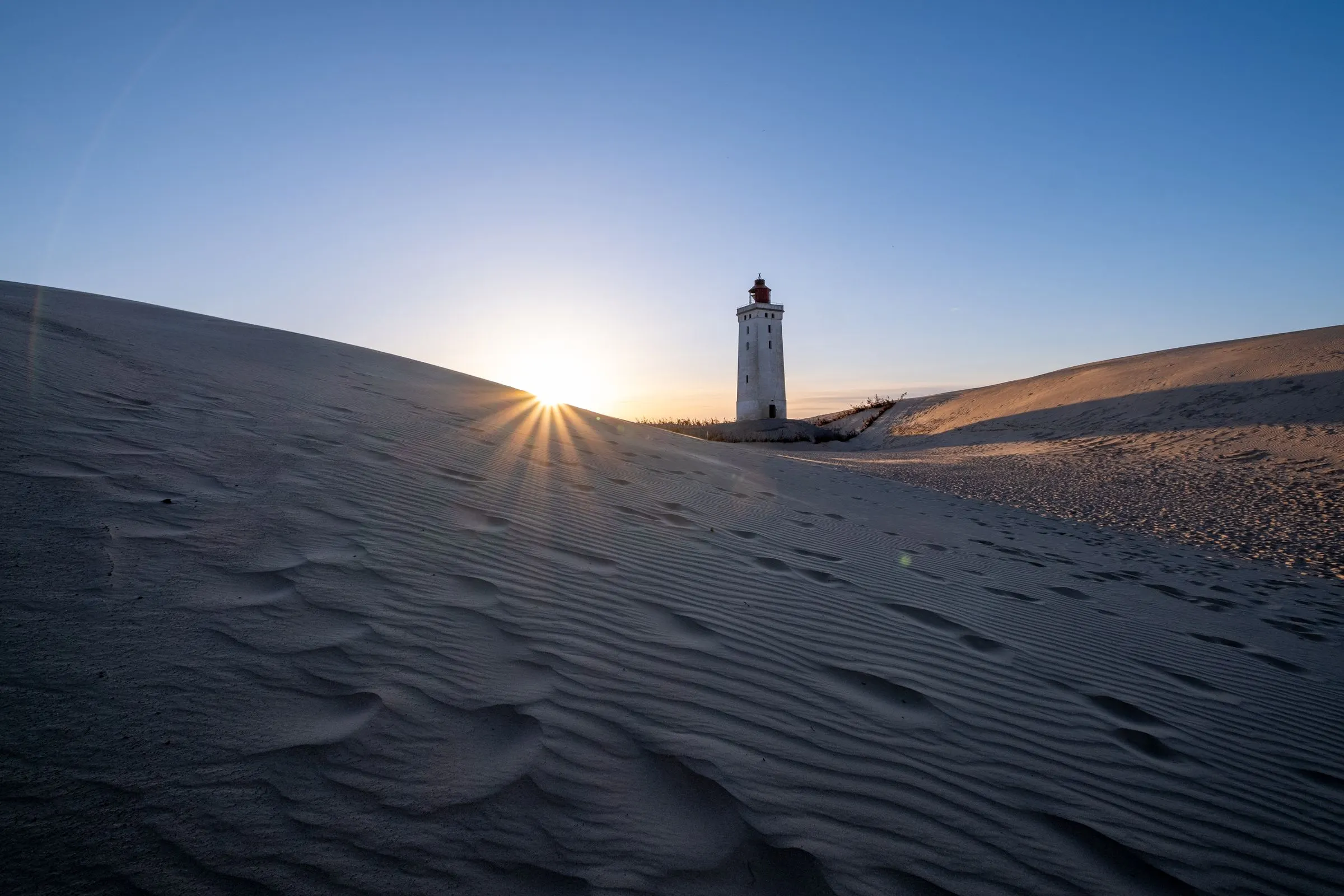 Vuurtoren op de duinen bij zonsondergang, Rubjerg Knude in Denemarken.